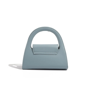 Detail of light blue trapezoid leather handbag with a unique circular handle and fine stitching