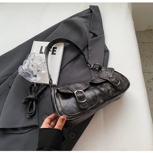Detail of vintage black crescent bag with textured faux leather and silver metal buckles
