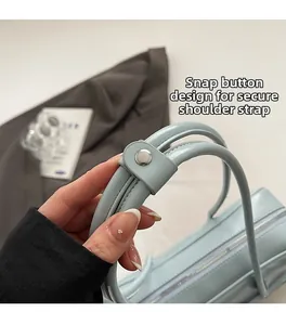 Detail view of the light blue handbag featuring silver snap buttons and fixed shoulder straps