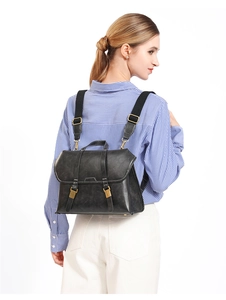 Dark grey vintage leather backpack with gold hardware shown from a side view on a model