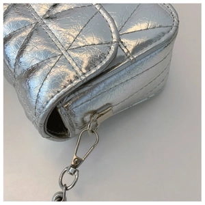 Detail of silver metallic quilted bag showing glossy finish and metal chain lobster clasp