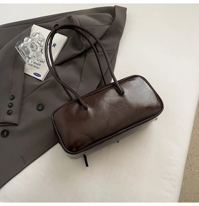Détail d'un sac à bandoulière en cuir verni marron foncé brillant à doubles lanières