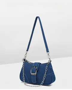 Détail du sac à bandoulière en denim bleu avec chaîne argentée et boucle décorative