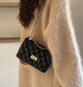 Détail du sac matelassé noir avec fermoir doré et bandoulière en chaîne sur un mannequin