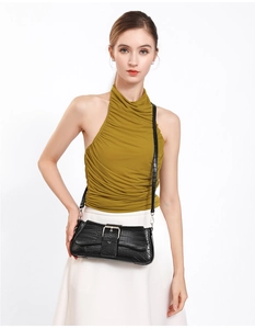 Detail of black stone-pattern baguette bag with silver buckle on yellow top and white skirt