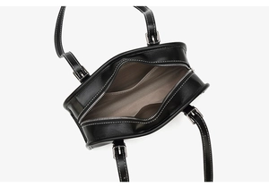 Top view of black leather handbag featuring contrast stitching and silver zipper detail