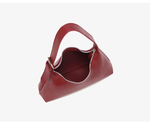 Detail view of the burgundy leather underarm bag featuring a silver zipper and crescent shape