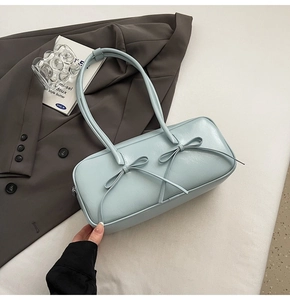 Détail du sac sous l'aisselle en similicuir bleu clair avec nœuds et doubles brides