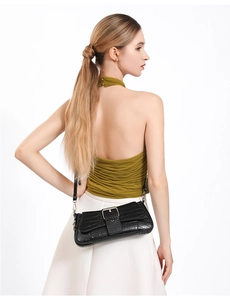 Detail of black faux crocodile skin texture and silver buckle on a stylish baguette bag