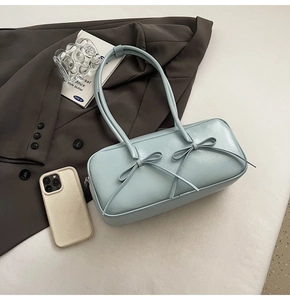 Gros plan d'un sac Boston bleu clair avec nœuds sur une veste de blazer gris foncé