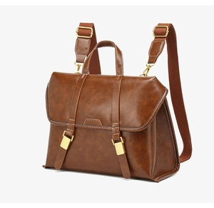 Detail of vintage brown leather backpack with golden metal buckles and white contrast stitching