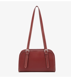 Detail view of burgundy leather shoulder bag with white stitching and silver metal buckles