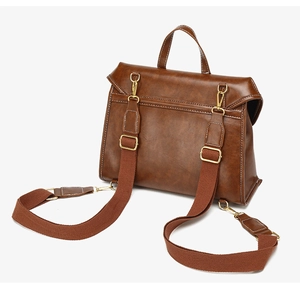 Detail of vintage brown leather backpack showing contrast stitching and gold metal hardware