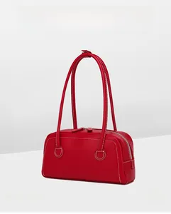 Detail of red leather shoulder bag with white contrast stitching and double zippers
