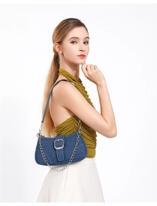 Détail du sac bandoulière en denim bleu avec boucle argentée, chaîne et surpiqûres