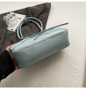 Gros plan sur le nœud en ruban bleu clair et la texture en cuir verni du sac Boston