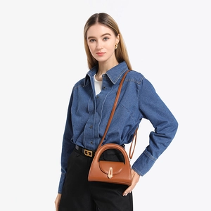 Brown semi-circular leather handbag with gold clasp and strap shown on a model