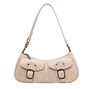 Detail of cream faux leather baguette bag with dual front pockets and metal buckle hardware