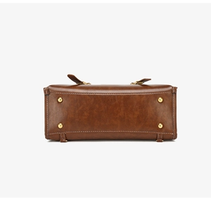 Close-up of vintage brown leather bag base with golden protective studs and white stitching
