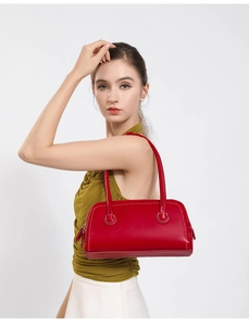 Close-up of a vintage red shoulder bag featuring white contrast stitching and zippers