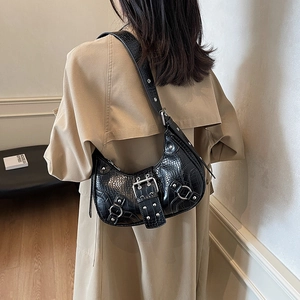 Black croc-embossed crescent shoulder bag detail, motorcycle style with metal buckles and rivets.