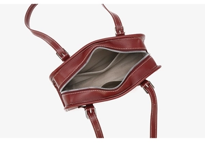 Detail view of burgundy handbag interior with herringbone lining and silver zipper