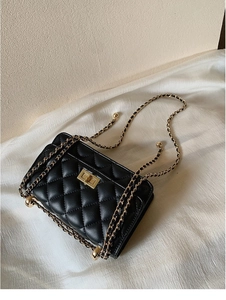 Détail du cuir matelassé noir avec bandoulière chaîne dorée et fermoir pivotant carré