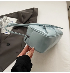 Détail d'un sac à bandoulière bleu clair brillant avec nœud et fermeture éclair argentée