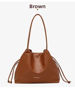 Detail einer braunen Kordelzug-Beuteltasche aus Leder mit modischem Logodruck
