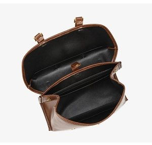 Detail view of the brown leather backpack showing multiple compartments and white stitching