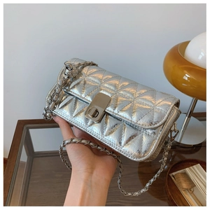 Close-up of silver quilted crossbody bag with metal chain strap and twist lock