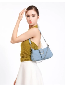 Détail du sac sous le bras en denim bleu clair avec chaîne argentée et boucle sur fond jaune