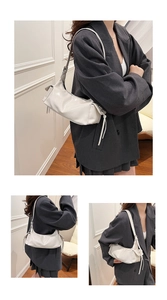 Detail of white patent leather shoulder bag featuring long tassel drawstrings and soft texture