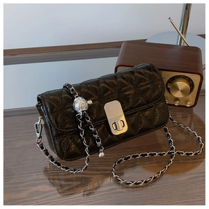 Close-up of black quilted chain bag with silver ball adjuster and sleek metal lock