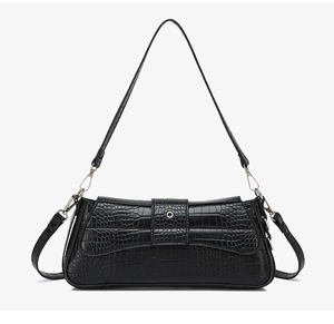 Detailed close-up of the black crocodile pattern leather and round metal buckle on the bag