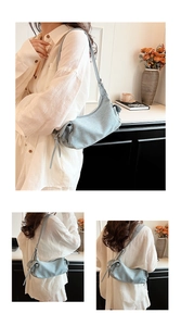 Light blue textured fabric shoulder bag featuring drawstring details shown on a model