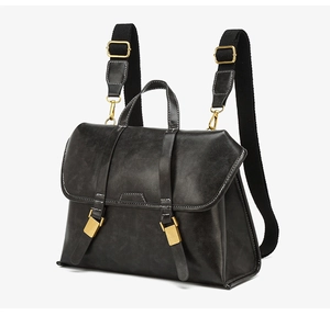 Close-up of black retro backpack with white contrast stitching and gold buckles
