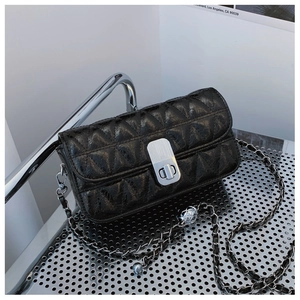 Detail of black quilted crossbody bag showing silver metal clasp and chain strap