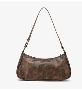 Detail of vintage brown crescent bag showing high-quality faux leather texture and metal chain