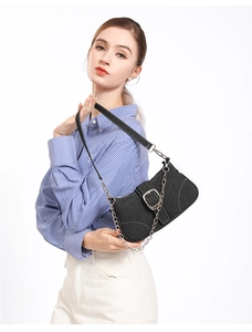Gros plan du sac sous le bras en toile noire avec boucle argentée et bandoulière chaîne