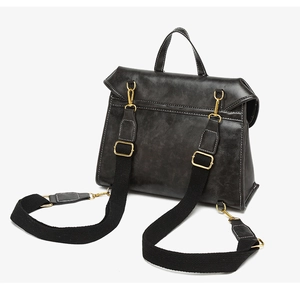 Detail view of adjustable woven straps and gold hardware on a black leather backpack