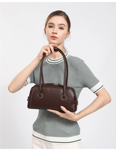 Detail of dark brown leather handbag with contrast stitching and slender handles