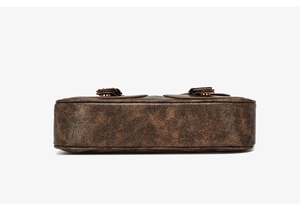 Detail view of the vintage brown leather texture and wide base of the crossbody bag