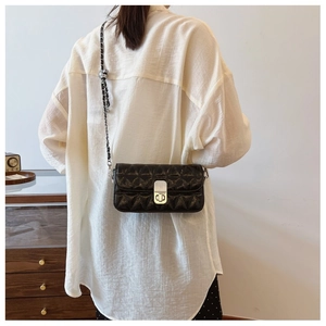 Detail view of black quilted crossbody bag featuring silver metal lock and chain strap