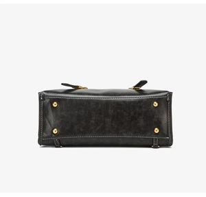 Detail of vintage black leather bag base featuring gold studs and white contrast stitching