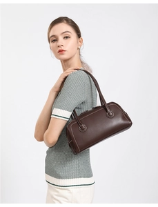 Detail view of dark brown Boston bag featuring white contrast stitching on leather surface