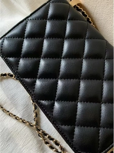 Détail de la texture cuir matelassé noir et bandoulière chaîne dorée du petit sac