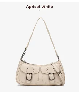 Detail view of apricot white shoulder bag with dual pockets and bronze metal buckle accents