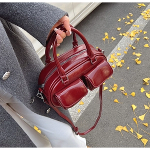 Detail view of glossy wine red leather bowling bag with twin flap pockets and top handles