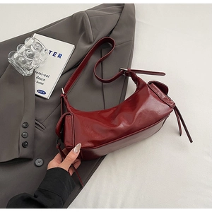 Detailed view of burgundy glossy faux leather texture and side lace-up design of the bag
